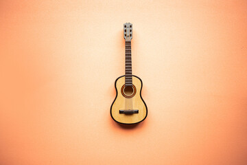 Toy acoustic guitar on pastel pink background