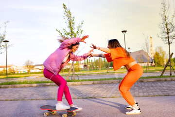 Ragazze in città che si divertono correndo sullo skateboard.