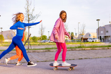 Ragazze in città che si divertono correndo sullo skateboard.