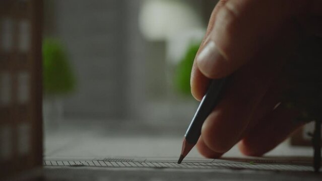 Industry. A modern design engineer in glasses uses a pencil for drawings in a modern development center. Designer-technologist uses a pencil to draw a line on a progressive urban landscape, work