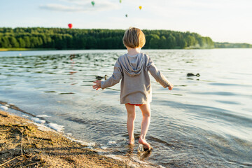 Cute little boy playing by a lake or river on hot summer day. Adorable child having fun outdoors during summer vacations. - 793868877