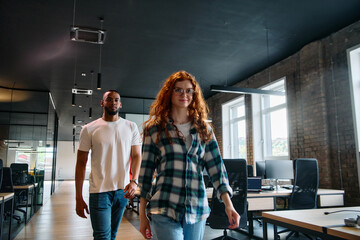 An African-American business colleague and his orange-haired female counterpart engage in collaborative discussion within a modern startup office, epitomizing diversity and teamwork in the
