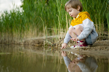 Cute little boy playing by a lake or river on hot summer day. Adorable child having fun outdoors during summer vacations. - 793871022