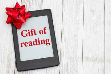 The gift of reading with an ereader with gift bow on an old weathered table