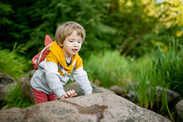 Cute little boy with a backpack having fun outdoors on sunny summer day. Child exploring nature. Kid going on a trip. - 793872618