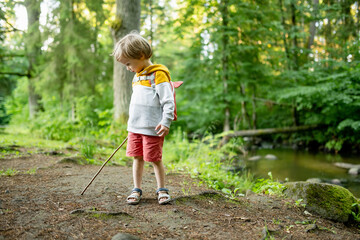 Cute little boy with a backpack having fun outdoors on sunny summer day. Child exploring nature. Kid going on a trip. - 793872697