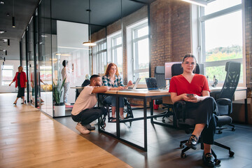 A diverse group of business professionals collaborates in a modern startup coworking center, utilizing a mix of paper-based and technological tools such as mobile phones and computers 