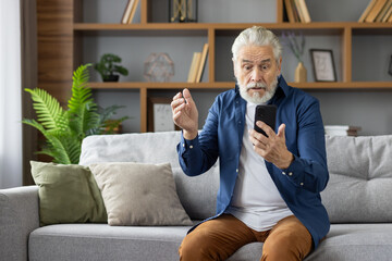 Senior man looking confused and worried while reading bad news on phone