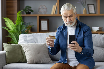 Senior man confused while using credit card and smartphone
