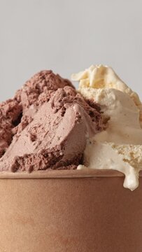Close up of roating vanilla and chocolate flavor ice cream in brown paper take away cup. Summer dessert