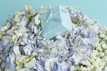 A gift box on a bouquet of hydrangea flowers on a blue background