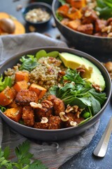 Bowl of vegan salad with quinoa, tofu, avocado, and mixed greens.