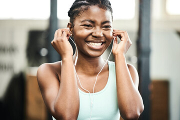Earphones, healthy and black girl in gym, music and listening for exercise, online and streaming on...