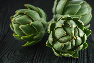 fresh natural artichokes on a black wooden background
