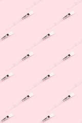 Pattern made of makeup brush with transparent handle on a pink background. Creative layout.