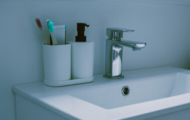 Minimal bath background with bamboo toothbrushes in white plastic glass on white background. Front view. Copy space. High quality photo in green blue tones.