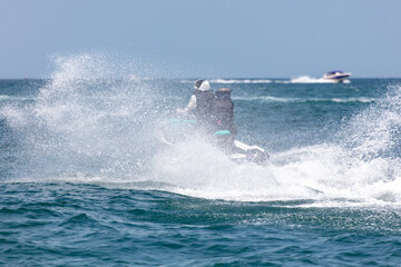 A water scooter rushes through the waves of the sea with splashes