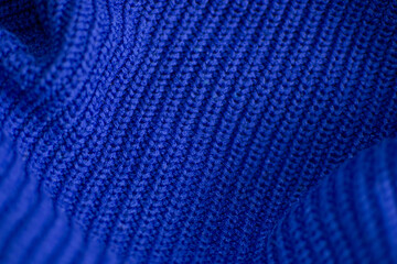 Detailed close-up view of a textured blue knitted material, showcasing intricate patterns and weaving. The rich blue hue adds depth and dimension to the fabric. Wallpaper of fabric.