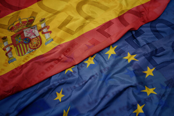 waving colorful flag of european union and national flag of spain.finance concept.