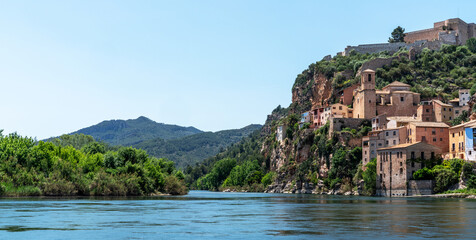 a picturesque riverside village Miravet, Spain. Ancient buildings clinging to the steep hillside,...