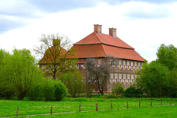 Fototapeta premium Westfälische Landschaft bei Hamm im Frühling mit Blick auf das Schloss Oberwerries hinter Bäumen, Römer-Lippe-Route, Sehenswürdigkeiten, Ausflug, Westfälischer Turnerbund