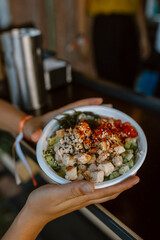 Crop woman eating appetizing poke in a music festival from a foodtruck