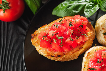 delicious Italian bruschetta with tomatoes on a black wooden rustic background