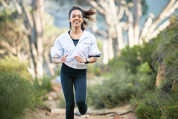 Woman, running and forest with smile for workout health or exercise cardio for performance, summer...