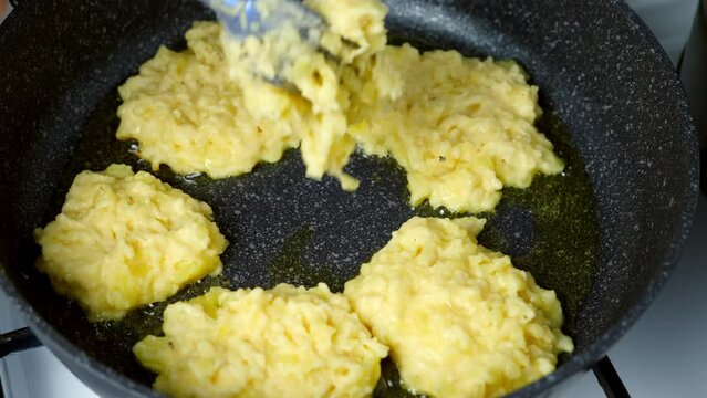 Potato pancakes, draniki cooking in frying pan on gas oven on kitchen at home. Preparing fresh dish. Cuisine, culinary, recipe. Traditional Russian food on lunch dinner fry on vegetable oil.