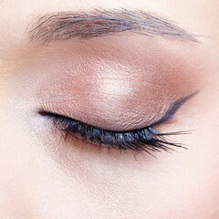 Closeup macro shot of human female closed, eye with black arrows. Woman with natural evening vogue face beauty makeup.