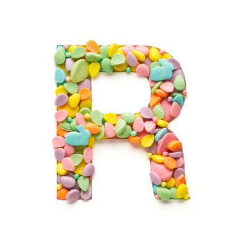 Capital letter is made of candies in the shape of Easter eggs on a white background.