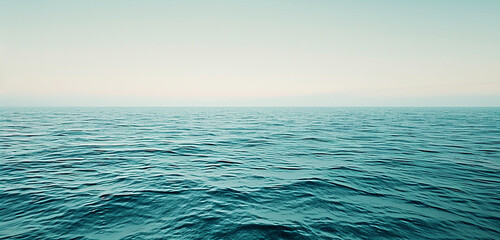 A panoramic view of a calm sea, blue gently faded near the horizon where it meets a pale, washed-out sky, capturing the quiet majesty of the marine landscape. 32k, full ultra hd, high resolution