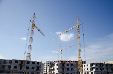 Urban construction of buildings, cranes on the background of the sky