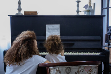 Funny Girl amd Happy Mother Play on Piano Together. Hobbies For Mother and Young Daughter. Happy Mother with Little Girl Play on Piano. Positive Day for Beautiful Woman. Young Daughter.