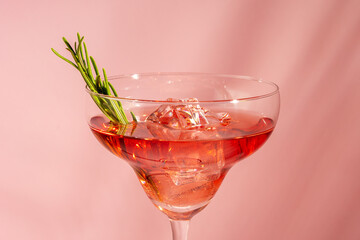 Refreshing cocktail with rosemary in a glass on a bright background. Summer party concept.