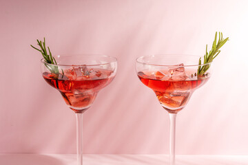 Refreshing cocktail with rosemary in a glass on a bright background. Summer party concept.