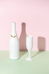 White champagne bottle and champagne glass on bright background.. Minimal party concept.