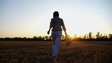 Female farmer running through the barley plantation at sunset. Agronomist jogging among wheat...