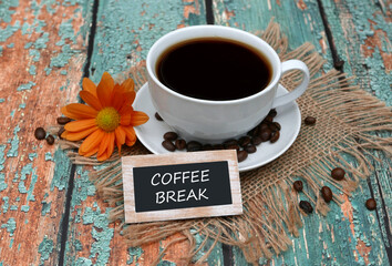 In front of a cup of coffee there is a sign that says coffee break.