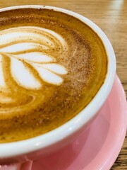 Cappuccino in a pink glass on a wooden table