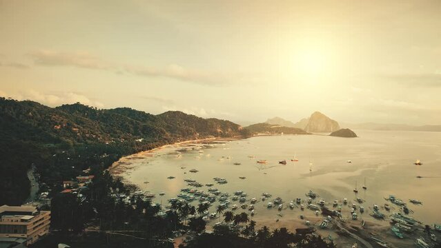 Ocean pier in sunset mountain lagoon. Sun light aerial view: Philippines, El Nido Islands, Palawan. Ships, boats, yachts at tropical paradise water. Vacation at exotic Island. Sea beach landscape