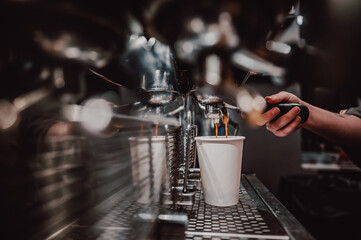 Skilled barista operating an espresso machine, filling a white cup with fresh coffee in a cozy café ambiance - obrazy, fototapety, plakaty