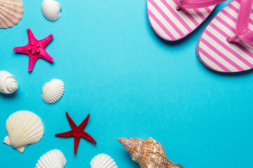 Creative composition with seashells and beach slippers on blue background. Summer minimal concept.