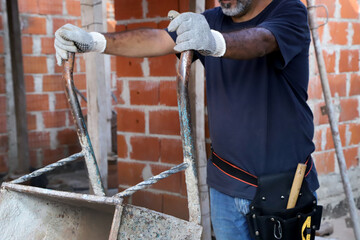 Bricklayer unoading wheelbarrow at construction site. Construction worker. Builder. Concept of...