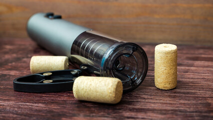 An electric corkscrew and wine bottle caps lie on dark wood table, preparing for the holiday.