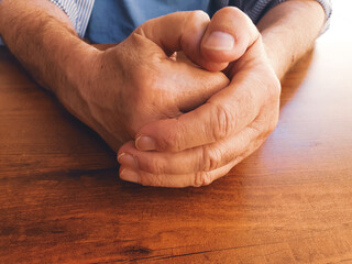 close up view of a stressed mature man on table , Hands of an elderly man folded together