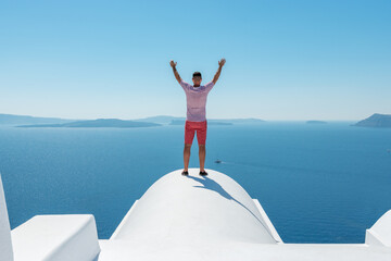 Man on the roof enjoying view of Santorini island and Caldera in Aegean sea. Greece.