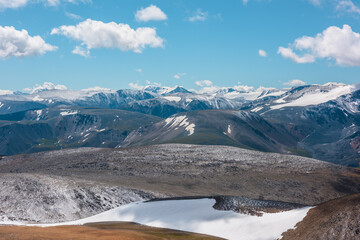 Aerial top view to snowy stony pass and large colorful mountain range in far away. Snow-white...