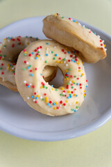 Small homemade donuts covered in white chocolate and colorful toppings