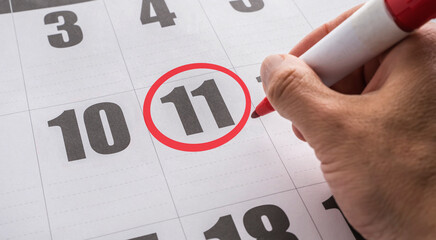 Hand drawing a red circle on the 11th of the calendar